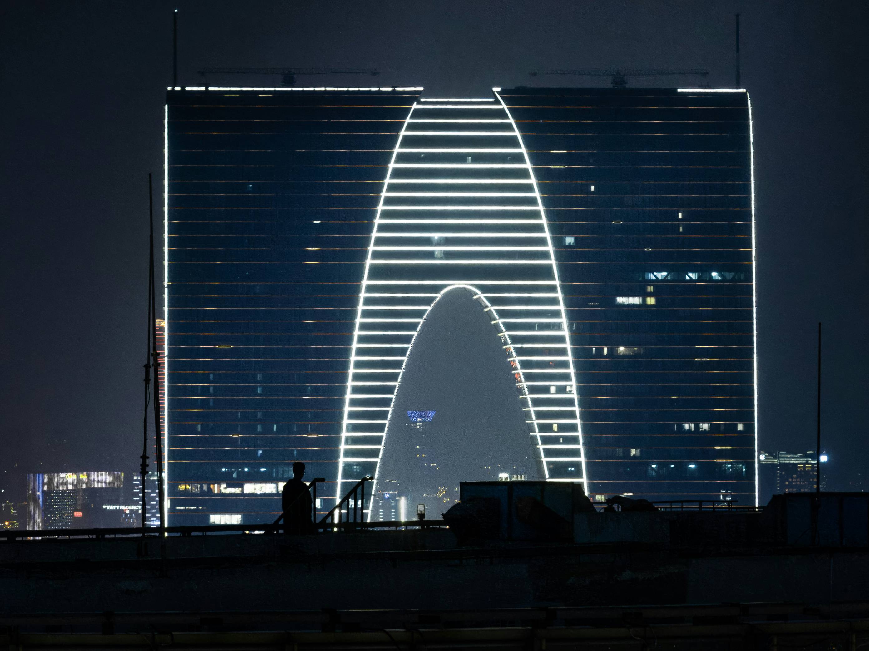 A lit, modern building towers over a city at night.