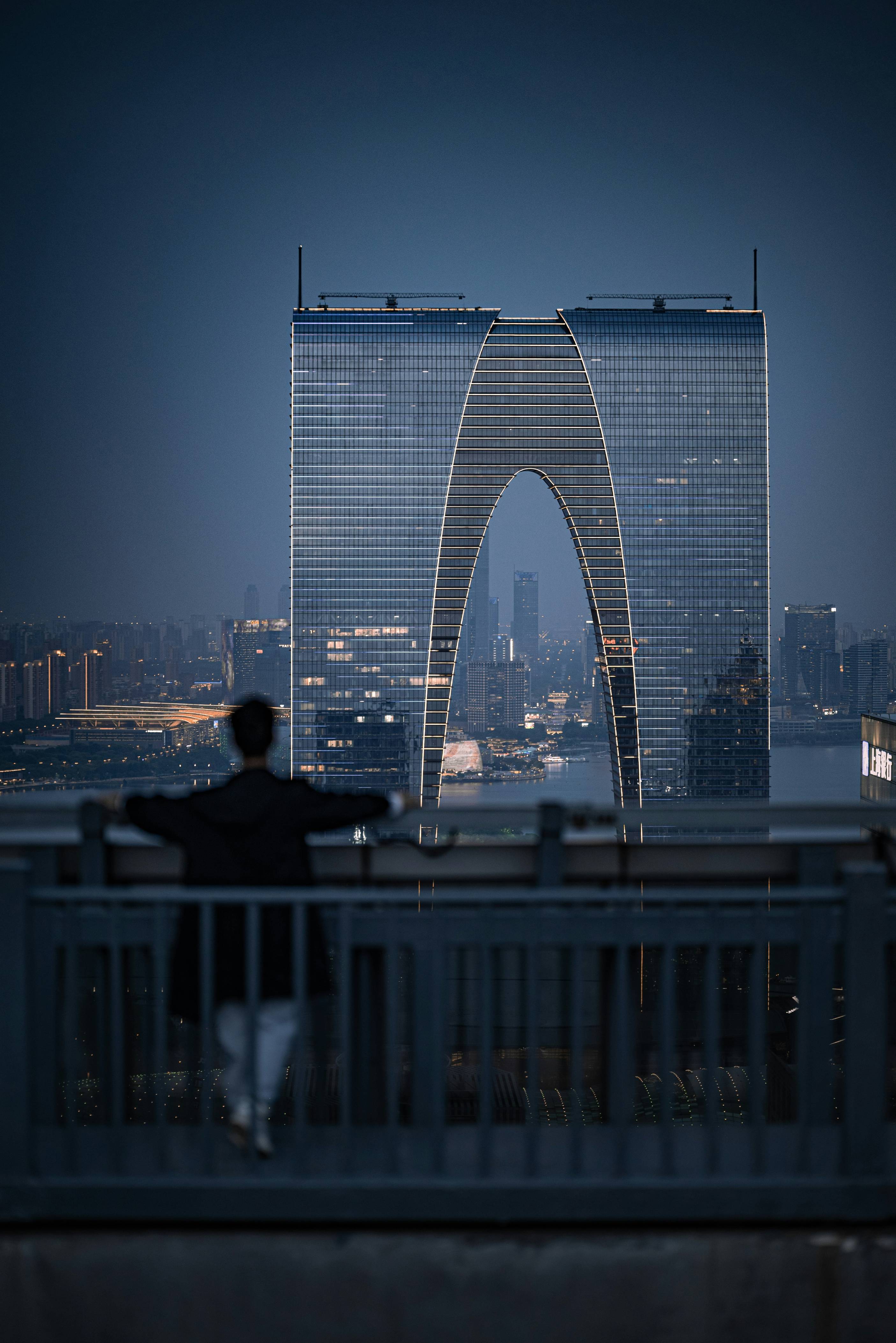 Person gazes at modern building at dusk.